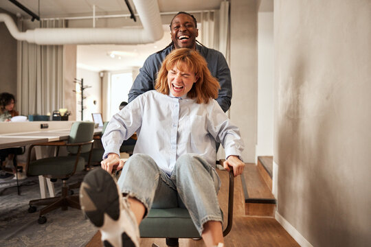 Man pushing a coworker in an office chair