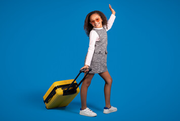 Happy teen african american curly girl tourist in sunglasses with suitcase enjoy travel