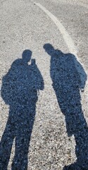 Shadow of two travelers with backpacks on the road