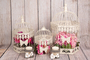Jaulas decorativas antiguas con ramos de flores y velas sobre fondo de madera.