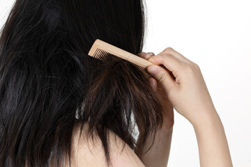 Hands combing damaged and tousled hair, back view