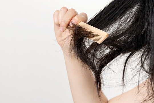 Hands combing damaged and tousled hair, back view