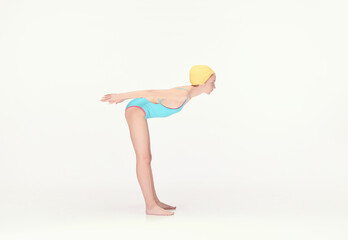 Young girl in blue swimsuit and yellow swimming cap standing in position to dive, training isolated over white background. Concept of retro style, sport, fashion, youth, vintage. Copy space for ad