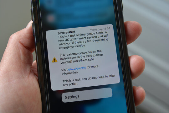 Cellphone in hand with screen showing test notification warning of Severe Alert, UK 