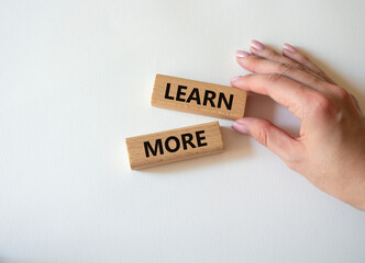 Learn more symbol. Concept word Learn more on wooden blocks. Beautiful white background. Businessman hand. Business and Learn more concept. Copy space