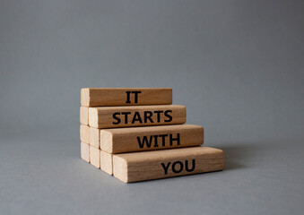 It starts with you symbol. Wooden blocks with words It starts with you. Beautiful grey background....