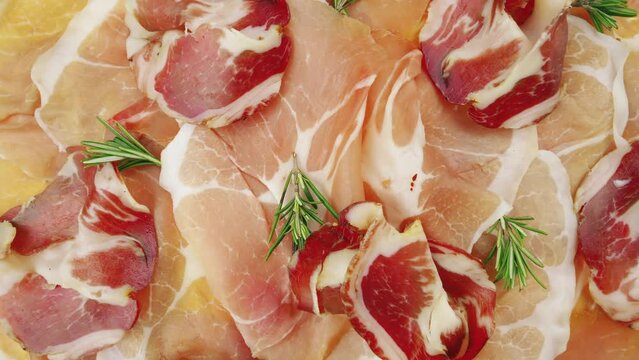 Rotating slices of raw ham. Prosciutto crudo, raw cured ham, view from top