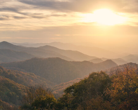 A beautiful sunset over the smoky mountains in North Carolina. It is a hazy day with a lot of clouds in the sky, but the sun is shining through for a beautiful image. 