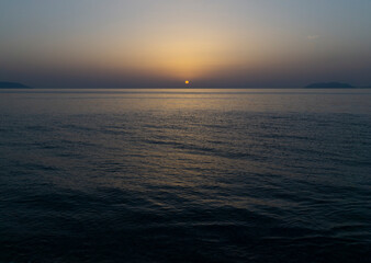 stunning blue and yellow sunset over mediterranean ocean with rounded orange sun and calm sea