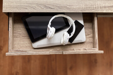 digital detox and technology concept - close up of different gadgets in desk drawer at home