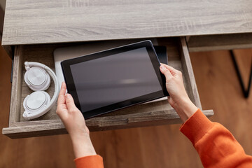 digital detox and technology concept - close up of hands holding tablet pc computer and different gadgets in desk drawer at home