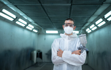 Auto mechanic in car spray room Inspecting the paint sprayed into the front bumper of the car that...