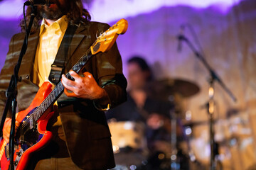 Band playing music and a gig in a venue, close up of a rock band playing guitars and instruments.