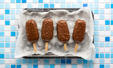 Ice cream eskimo flat lay. Top view of a chocolate-glazed popsicle with crushed nuts, served on a...
