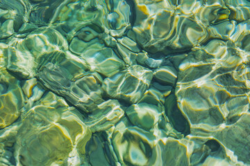 Blurred background of transparent clear water in the sea bay of the Aegean Sea glistens in the sun, idea for a background or postcard