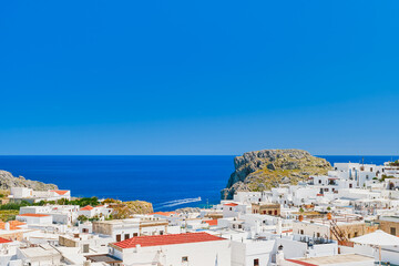 Rooftop view of the city of Lindos and the emerald sea with passing boats, Rhodes island, Greek...