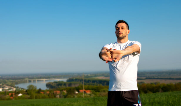 young guy stretches his arms in nature, healthy lifestyle, training as a lifestyle

