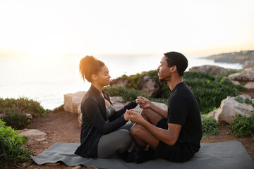Cheerful millennial african american female and male in sportswear practice yoga on ocean beach at morning