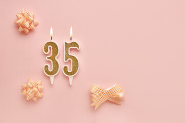 Number 35 on a pastel pink background with festive decorations. Happy birthday candles. The concept of celebrating a birthday, anniversary, important date, holiday. Copy space. banner