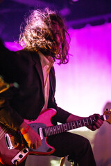 Band playing music and a gig in a venue, close up of a rock band playing guitars and instruments.