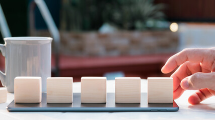 hand holding wood cube blurry background