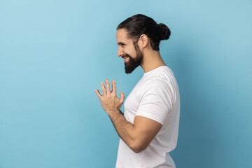 Side view of devious man with beard wearing white T-shirt smirking and conspiring cunning sly plan,...