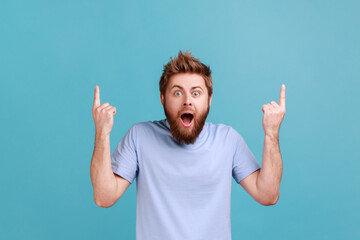 Wow, attention to advertising above. Portrait of bearded man pointing up at copy space and looking...