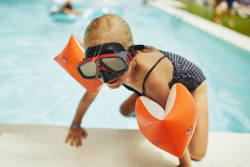 Cute little girl climbing out of a swimming pool
