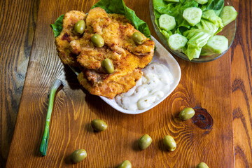 Fried chicken with sauce and olives on the kitchen table...