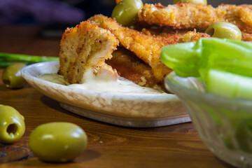 Fried chicken with sauce and olives on the kitchen table...