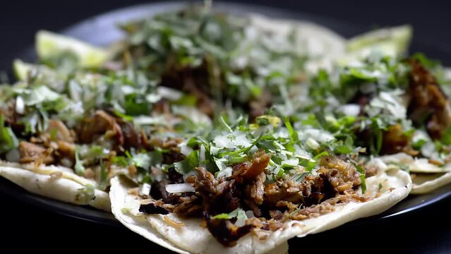 Green Salsa Being Poured Onto Mexican Carnitas Tacos