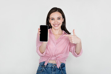 Fototapeta premium Cheerful young woman showing phone with blank screen