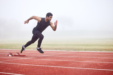 The perfect getaway. Full length shot of a handsome young male athlete running on an outdoor track.