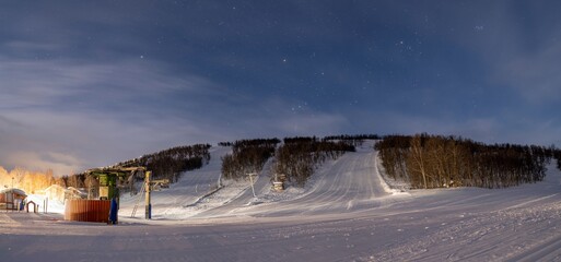Nighttime with Starry Sky at the Ski Lift in Ramundberget Resort area in Sweden with empty Slopes and no Skier in newly Groomed Piste.