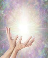 Magical Energy Healing Hands Sensing star light - ethereal pastel coloured background with a large golden star orb and female open palm hands reaching into energy with copy space
