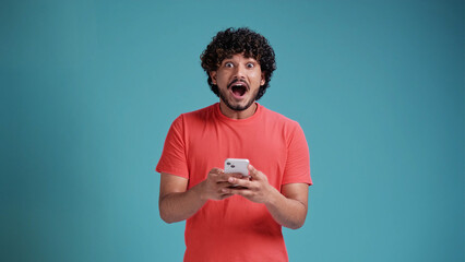 Funny surprised trendy guy suddenly read message on his mobile phone and expressing shock...