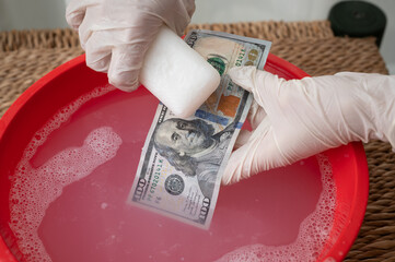 Closeup of hanMoney laundering concept. Hands washing 100 dollars banknote with soapds washing 100 dollars banknote with soap