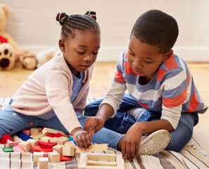 Theyre going to build the highest tower. two siblings playing in their room at home.