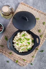 Stewed rice with chicken in a pot on grey background. Top view