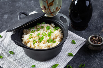 Stewed rice with chicken in a pot on dark grey background