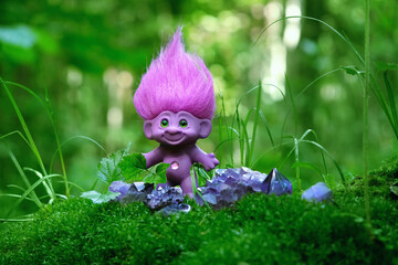 cute troll toy and amethyst minerals in forest close up, natural green background. fairytale pixie with ruffled violet hair in mystery forest. beautiful magic atmosphere. template for design - obrazy, fototapety, plakaty
