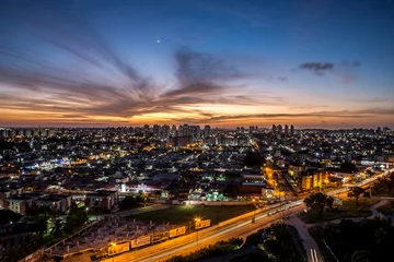 Foto op Canvas Sunset seen from above the building with orange and blue colored sky with the moon in the center and avenues and buildings highlighted.   Avenida Ayrton Senna em Natal, RN. © Laíne Paiva