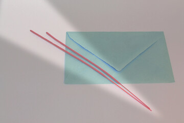 View of a blue envelope with sunbeam and red sticks on a gray background
