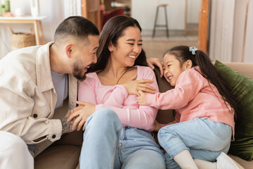 Chinese Parents And Little Daughter Cuddling Having Fun At Home