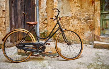 Fototapeta na wymiar Old retro bicycle on vintage street in Croatia background aged wall and wooden door. City Lovran