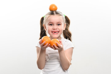 Portrait of a small beautiful girl on a white background with tangerines in her hands.