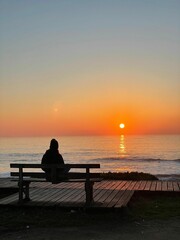 Fototapeta na wymiar Reflexões ao Pôr do Sol: Uma Mulher Contemplando a Vida em uma Praia do Norte de Portugal