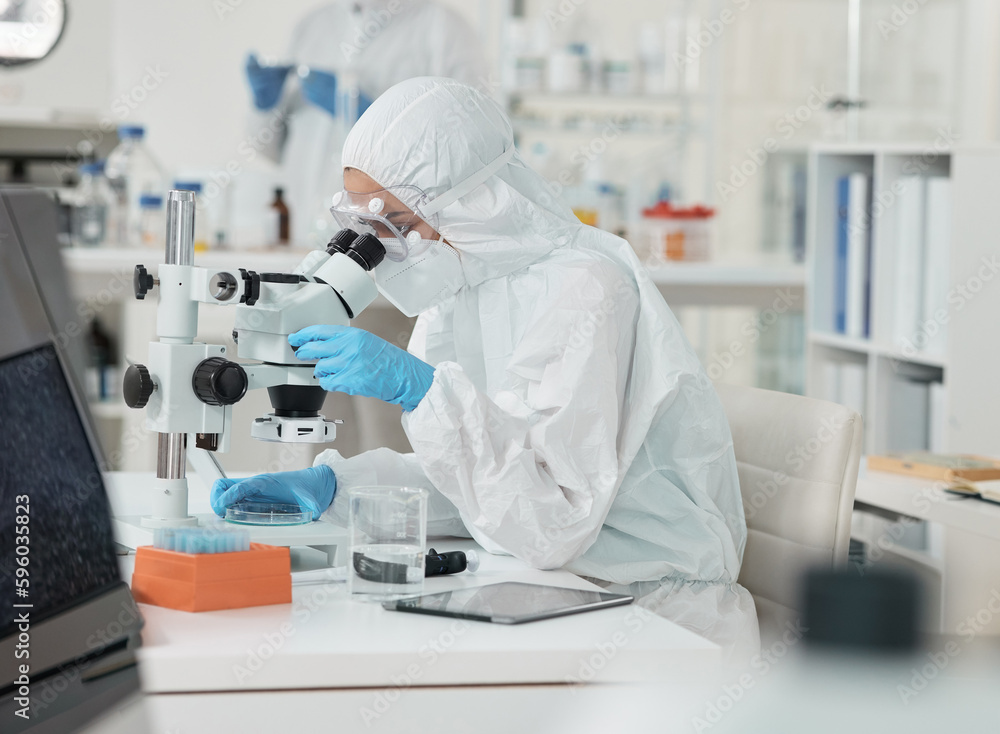 Poster Its clear to see now. a scientist wearing a radiation suit while using a microscope in a lab.