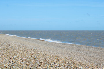 Beach scene with shingle beach in foreground and gentle waves in background