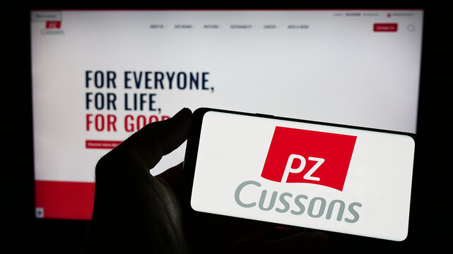 Stuttgart, Germany - 04-20-2023: Person holding smartphone with logo of British consumer goods company PZ Cussons plc on screen in front of website. Focus on phone display.